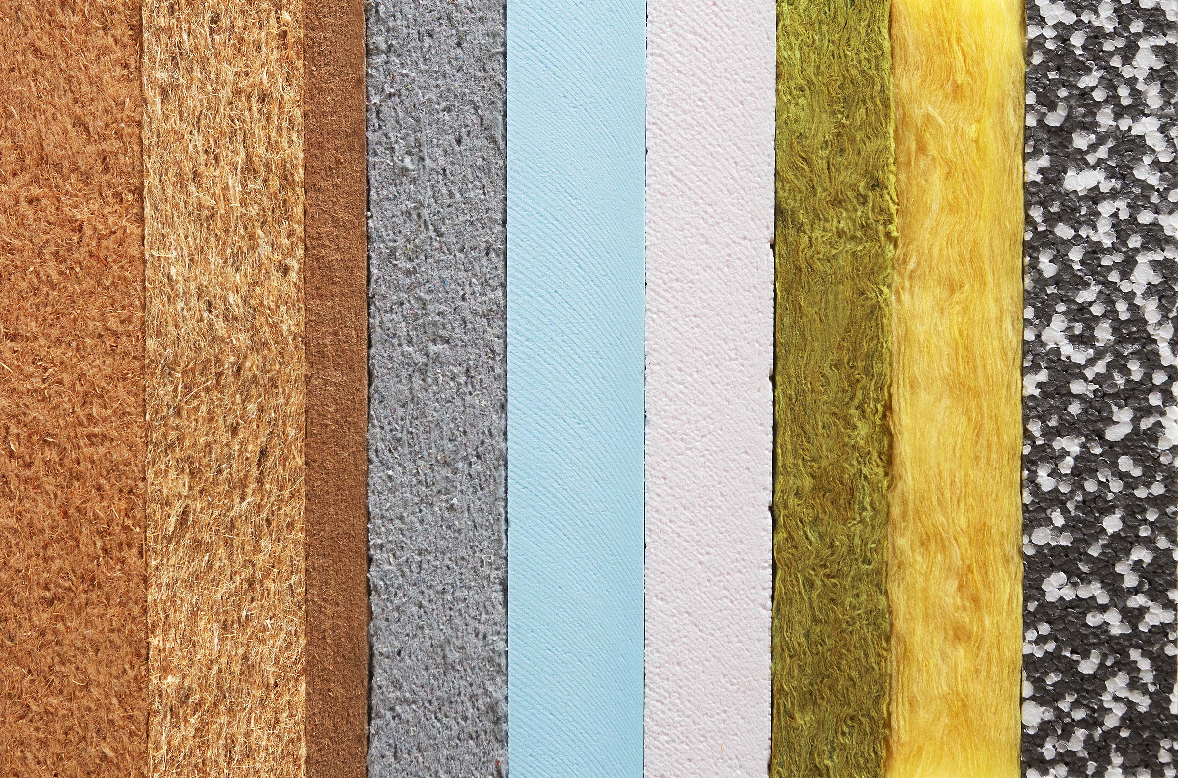 Dämmstoffe für ein perfektes Raumklima Verschiedene Dämmstoffe in vertikalen Streifen: braun, grau, blau, rosa, grün, gelb und schwarz-weiß.