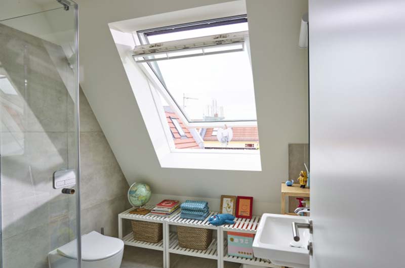 Belichtung & Dachfenster für mehr Wohnqualität Helles Badezimmer mit großes Dachfenster, Toilette, Waschbecken und Regal mit Körben und Dekoration.